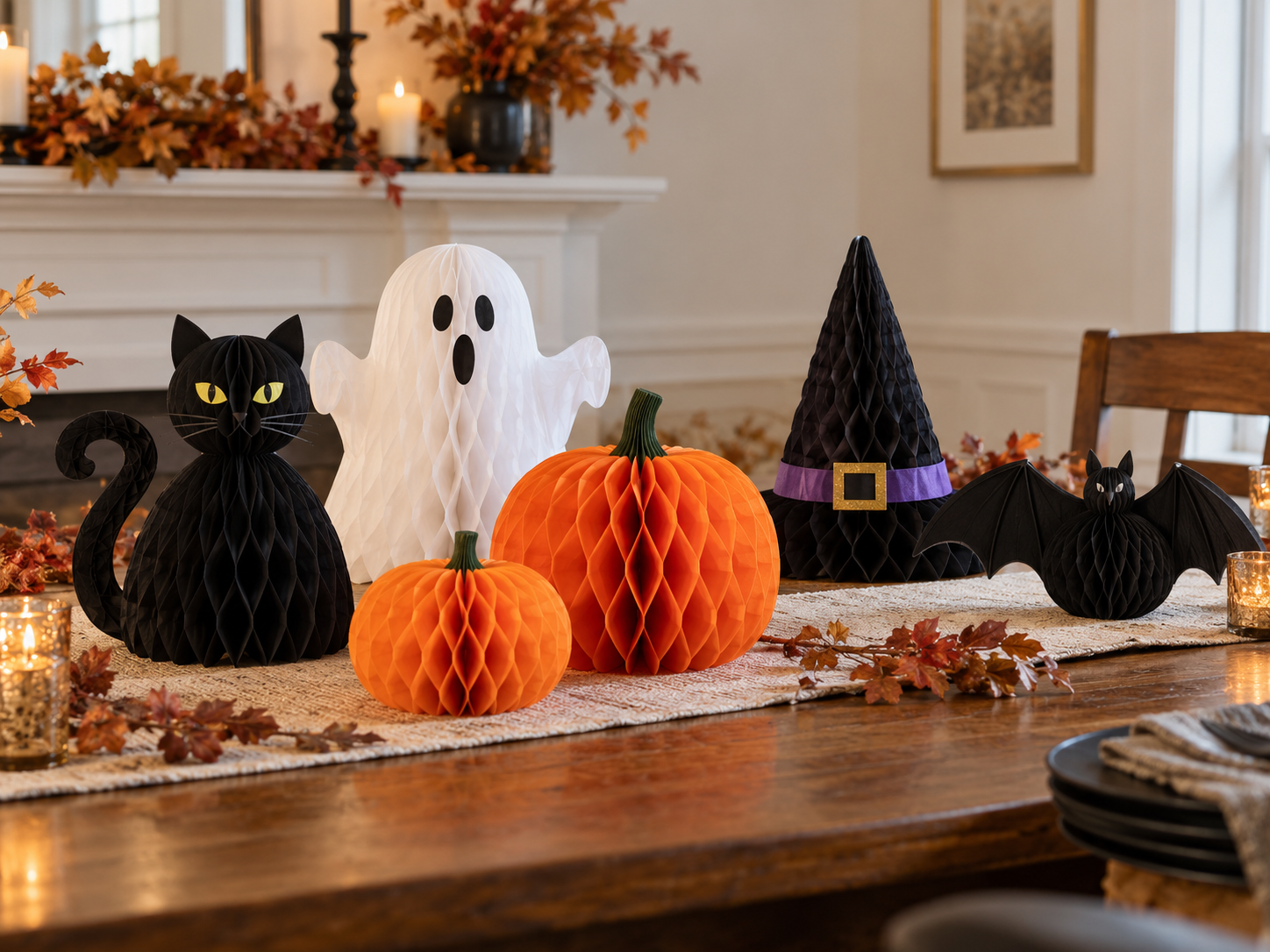 Halloween honeycomb paper centerpieces with pumpkins, ghost, cat, witch hat and bats on a dining table