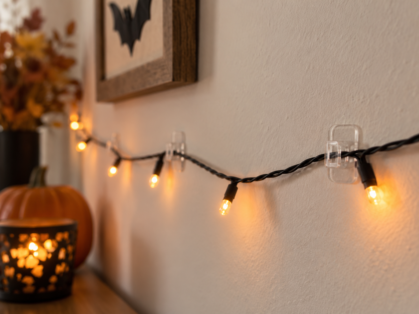 Command Mini Light Clips holding a lightweight Halloween string light along an indoor wall